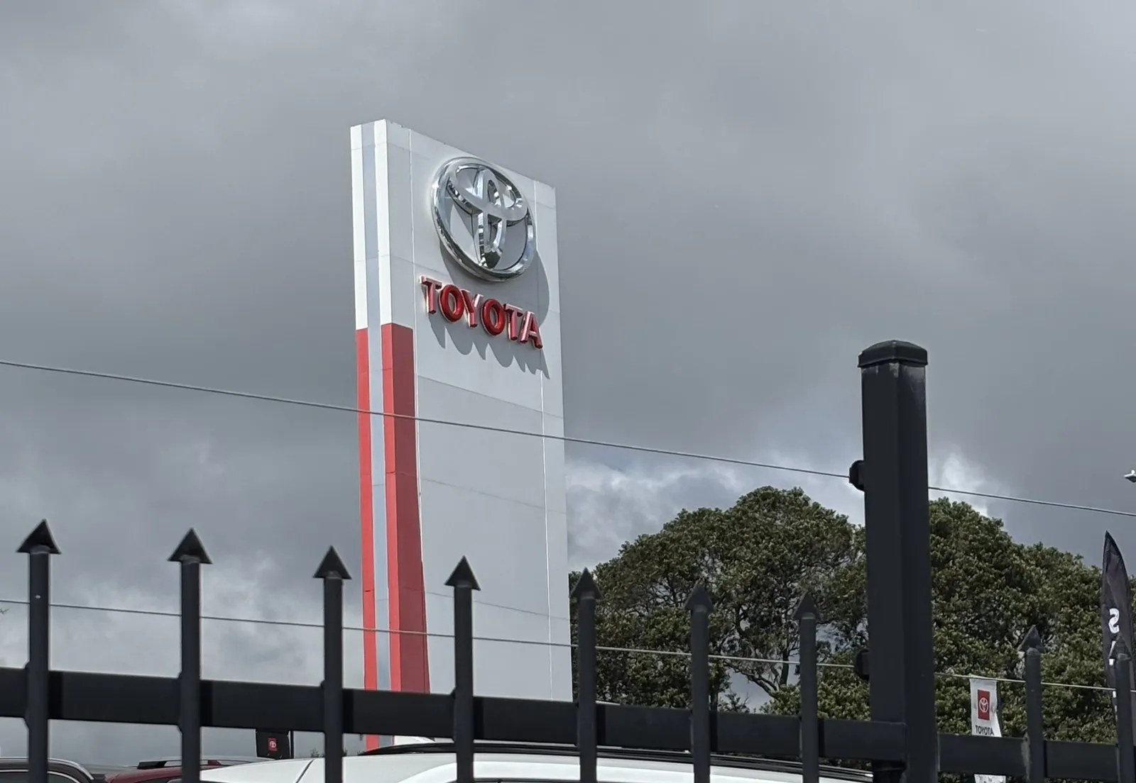 The entrance signage of a car dealership standing above its boundary fence