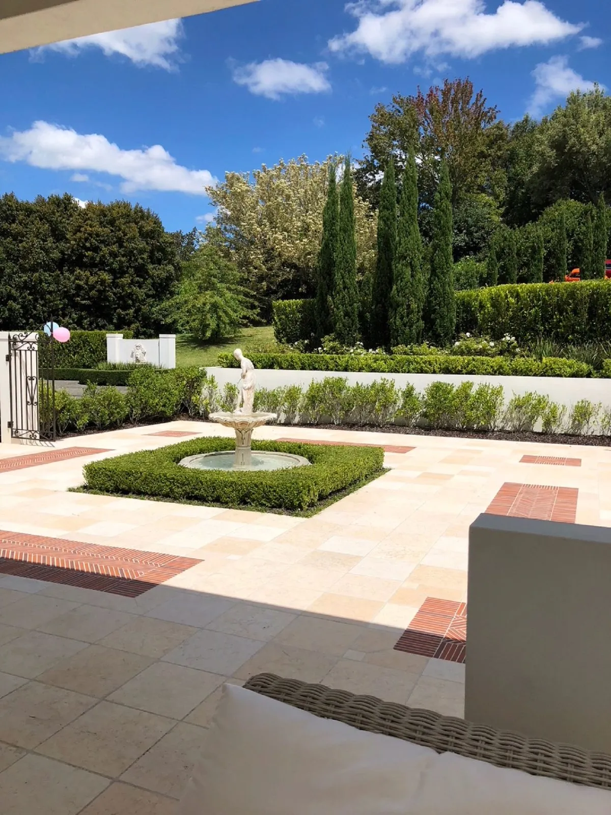 A formal courtyard garden with a statue centrepiece, clipped hedging and patterned paving